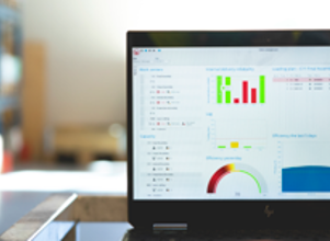 Dataskjerm som viser dashbord med grafer, indikatorer og analyser, plassert på en arbeidsflate i et industrielt eller teknologisk miljø.