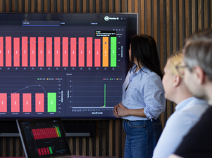 Three people in a conference room looking at a graph.